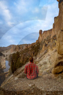 A man wearing flannel looking at a large rock formation.