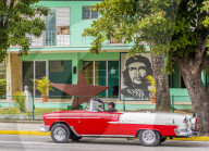 An old American car driving past a mural of Che Guevara, in Varadero, Cuba.