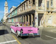 A view of a vintage American car in a typically colourful street in Havana, Cuba, Caribbean.