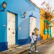 A street vendor walking past a colourful building in the old town in Cartagena, Colombia, South America.