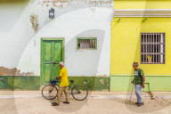Local men walking past typically colourful colonial architecture in Trinidad, Cuba, Caribbean, Central America.