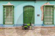 A motorbike in a typically colourful colonial street in Trinidad, Cuba, Caribbean, Central America.