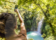 A tourist taking a picture of the Rio Celeste waterfall in Tenorio Volcano National Park, in Costa Rica, Central America.