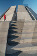 Woman in red walks past Armenian Genocide Memorial building, Yeravan, Armenia