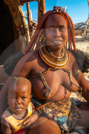 Red ochred, bare breasted Himba woman in trad dress, with her child, Puros Village, nr Sesfontein, Namibia (Model Release)
