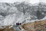 Hikers on the Miner's Track at base of mount Snowdon in a wintry landscape in the Snowdonia National Park, Gwynydd, Wales, UK.