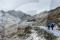 Hikers on the Miner's Track at base of mount Snowdon in a wintry landscape in the Snowdonia National Park, Gwynydd, Wales, UK.