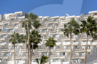 Apartment block and palm trees, overlooking Playa del Matorral, at Morro Jable, on the volcanic Canaries Island of Fuerteventura