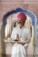 India, Rajasthan, Jaipur, Samode Palace, Waiter carrying Tea Tray in ornate passageway - Model and Property released