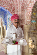 India, Rajasthan, Jaipur, Samode Palace, Waiter carrying Tea Tray in ornate passageway - Model and Property released