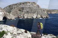 A woman hiking above sea cliffs near The Blue Grotto, south Malta