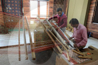 Two men working together to weave a complex double ikat Patola sari using a harness loom slanted to one side, Patan, Gujarat