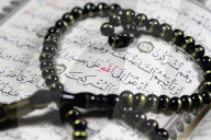 Quran and Tasbih (prayer beads). Allah monogram in red.
