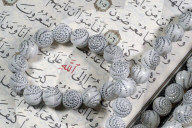 Quran and Tasbih (prayer beads). Allah monogram in red.