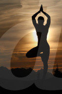 Silhouette of a woman practicing yoga against the light of the evening sun. Vrksasana, tree pose. French Alps. France.
