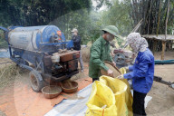 Rice workers feed their freshly harvested rice into a threshing machine. Lang Son. Vietnam.