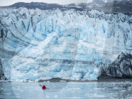 A kayaker paddling in front of Lamplugh Glacier, Glacier Bay National Park and Preserve, Alaska, USA.