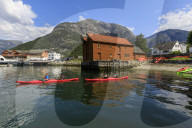 Sea kayakers head off, beautiful Eidfjord village, mountains and beach, sunny day, Norwegian Western Fjords, Norway