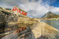 Traditional red cabin (Rorbu) with Mount Olstind (Olstinden) on background, Reine, Moskenes, Nordland, Lofoten Islands, Norway
