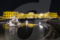 Marble statues of the Naiad Fountain in front of the illuminated Schonbrunn Palace, Vienna, Austria