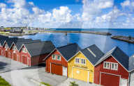 Traditional wood houses waterfront along the fjord, Alnes, Godoya Island, Alesund, More og Romsdal County, Norway (drone)