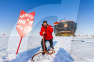 Man pretending to pull the Icebreaker '50 years of victory' on the North Pole, Arctic