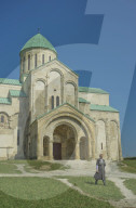 Priest walking by exterior of Bagrati Christian Orthodox Cathedral in Kutaisi,Georgia