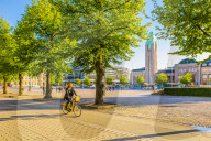 A woman cycling in Helsinki with Rautatieasema Train Station in the background, Helsinki, Finland, Scandinavia, Europe