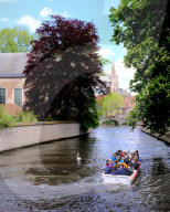 Tourist boat in the canals of Bruges with the Church of our Lady in the background, Bruges, Belgium, Europe