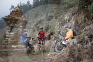 Mountain bikers take a break near a moss covered Tibetan chorten in the Himalayas in the Gosainkund region
