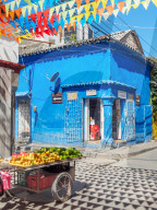 Colorful flags, blue building, and fruit cart on a street corner in Getsemani barrio, Cartagena, Colombia, South America