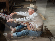 Indiginous man weaving with a backstrap loom, Otavalo, Ecuador, South America
