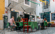 Tourists at a terrace of a restaurant serving traditional Portuguese food in the old district of Alfama, Lisbon, Portugal