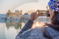 December 2018 - The Golden Temple in Amritsar, India. An Indian lady takes a smartphone picture of the Golden Temple at sunset