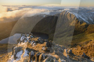 Morning light illuminates the top of Craig Cau during a cloud inversion, photographed from the top of Cadair Idris, Snowdonia.