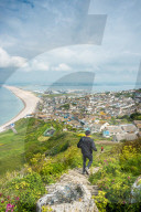Joggers take the path down to Chesil Beach from Portland heights on the Isle of Portland, Dorset, England, UK.