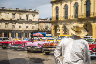 Cuban man overlooking colourful old American taxi cars parked in Havana, La Habana, Cuba, West Indies, Caribbean Central America