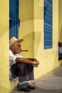An elderly Cuban sitting on a doorstep, smoking a cigar, Trinidad, Sancti Spiritus Province, Cuba, Central America