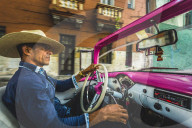 Local classic car driver at sunset in La Habana, Havana, Cuba, West Indies, Caribbean, Central America