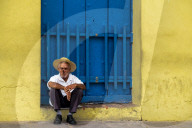 An elderly Cuban sitting on a doorstep, smoking a cigar, Trinidad, Sancti Spiritus Province, Cuba, Central America