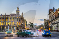 Vintage American cars turningand The Gran Teatro de La Habana at dusk, UNESCO, Havana, Cuba, West Indies, Caribbean
