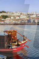 Porto, Portugal Vila Nova de Gaia waterfront evening view. Moored Douro river tourist ships before buildings & Porto wine shops.