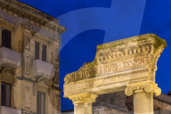 Illuminated entrance gate of the ancient Amphitheatre of Catania at dusk, Catania, Sicily, Italy, Europe
