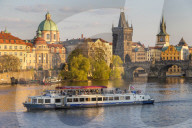 Tourist boat passing Charles Bridge and the Old Town Bridge Tower on Vltava River, Prague, Bohemia, Czech Republic, Europe