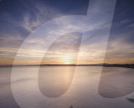 With interesting wispy clouds, the sun sets across the water from Exmouth, Devon, UK