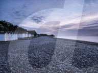 Twilight scene with beach huts and dew laden glistening pebbles on the beach at Budliegh Salterton, Devon, UK