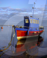Boat moored on the shoreline of the calm Exe Estuary, Exmouth, Devon, UK