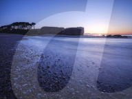 Sunrise behind the silhouetted cliff of Otter Head, where the River Otter meets the sea at Budliegh Salterton, Devon, UK