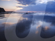 Sun rays and clouds reflections on the beach at Orcombe Point, Exmouth, Devon, UK.