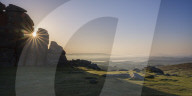 Sun breaks through a gap in granite rocks at Haytor in Dartmoor National Park, Bovey Tracey, Devon UK